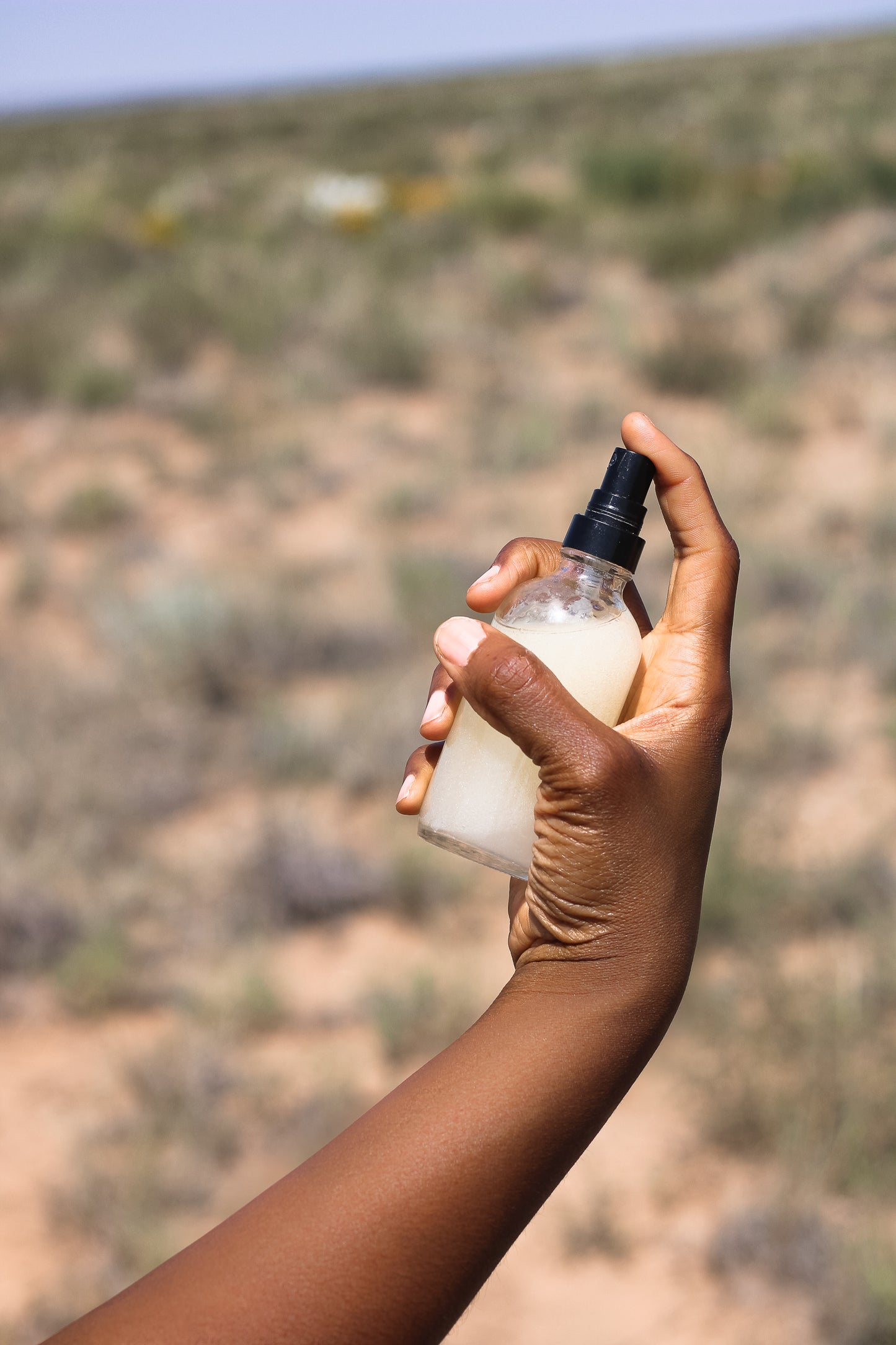 Non-Tacky Mosquito and Gnat Repellant Refreshing Spray in Ayanna's hand with desert background